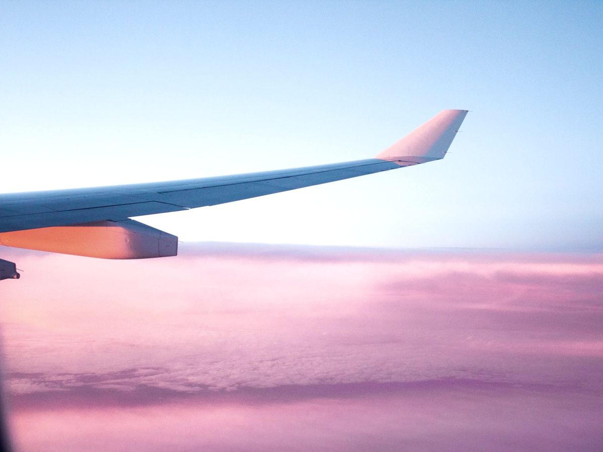 An aircraft wing above pink clouds